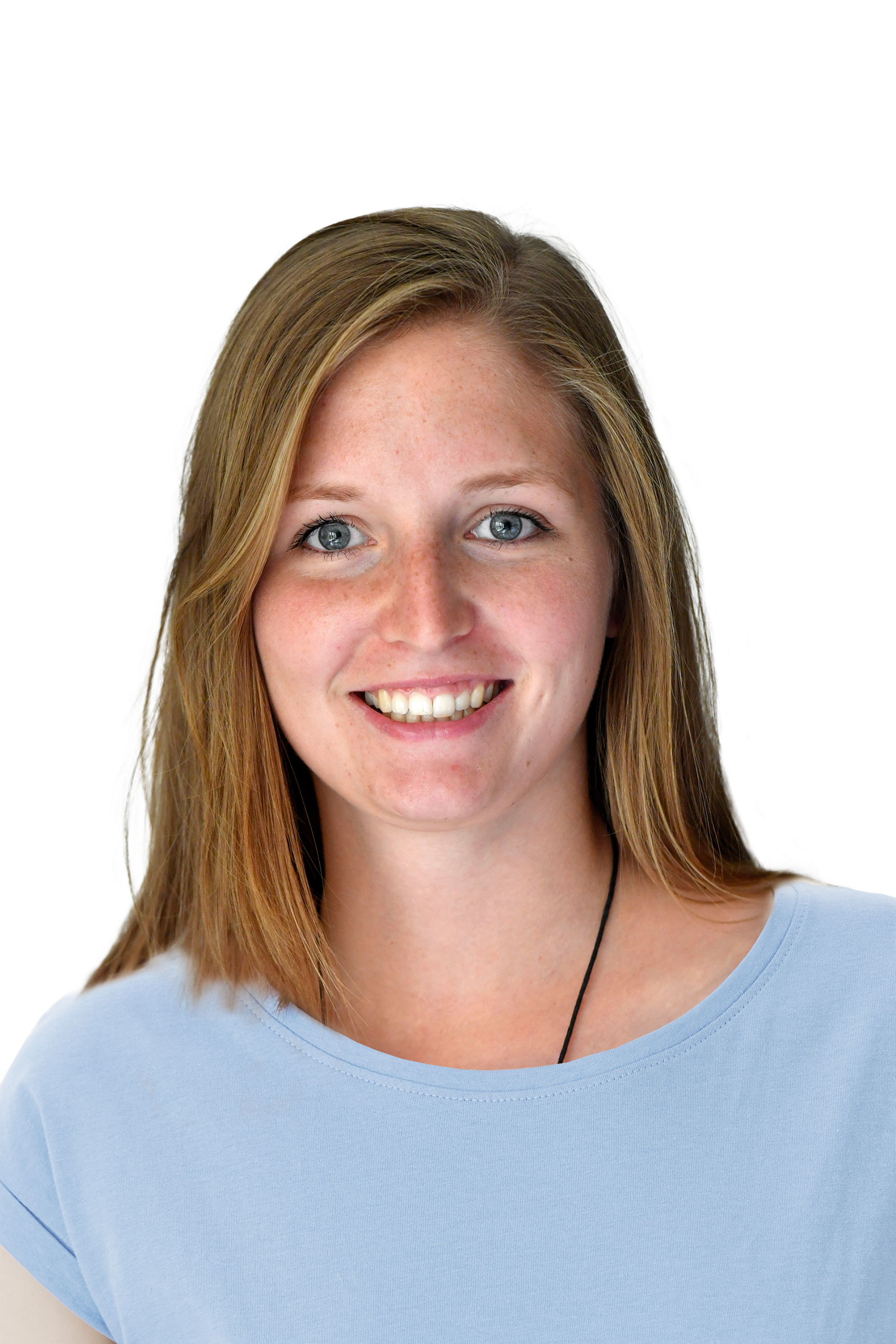 Porträt einer lächelnden Frau mit blonden Haaren, die ein hellblaues Shirt trägt, vor schwarzem Hintergrund.
