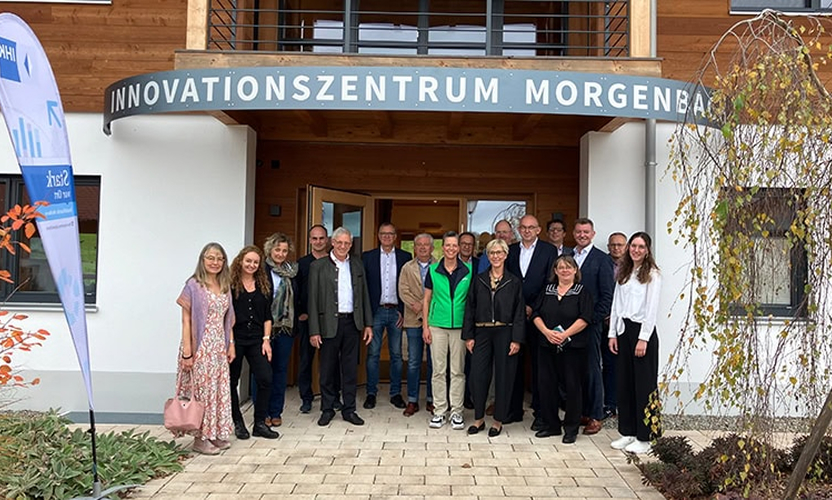 Gruppe von Personen steht vor einem Gebäude mit der Aufschrift „Innovationszentrum Morgenbacht“.