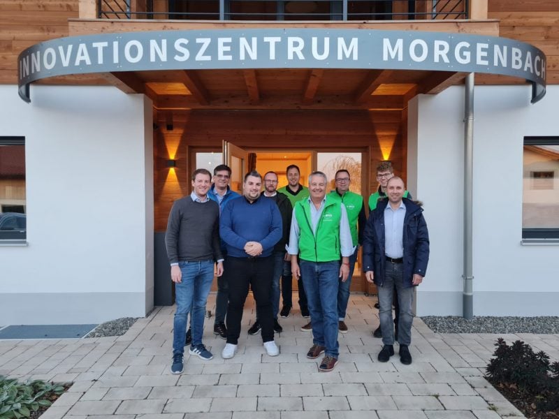 Gruppenbild vor dem Innovationszentrum Morgenbach von Teammitgliedern der Firma ECE Marketplace in grünen Westen und formeller Kleidung.