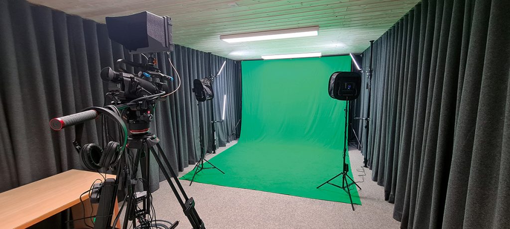 Professionelles Studio mit Kamera, Green Screen und Beleuchtung für Videoproduktion und Fotografie.