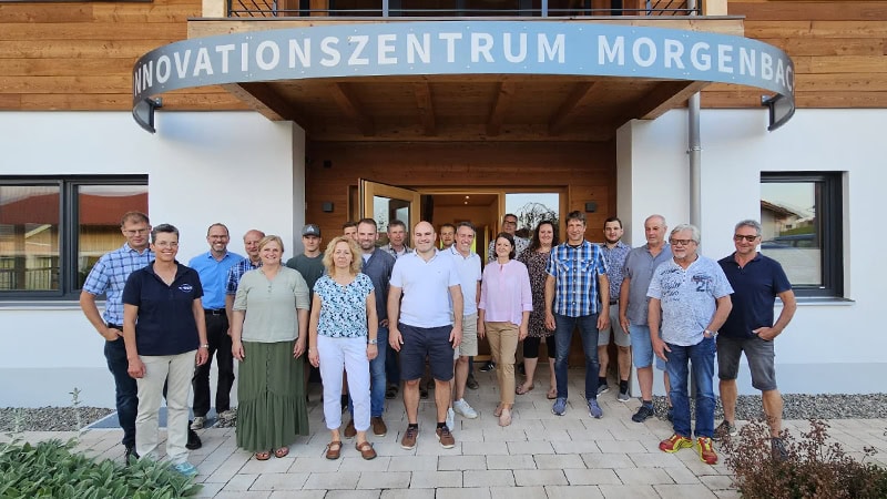 Gruppenbild vor dem Gebäude des Innovationszentrums Morgenbach von Mitgliedern des JHV Gewerbeverbands. Moderne Architektur und natürliches Licht.
